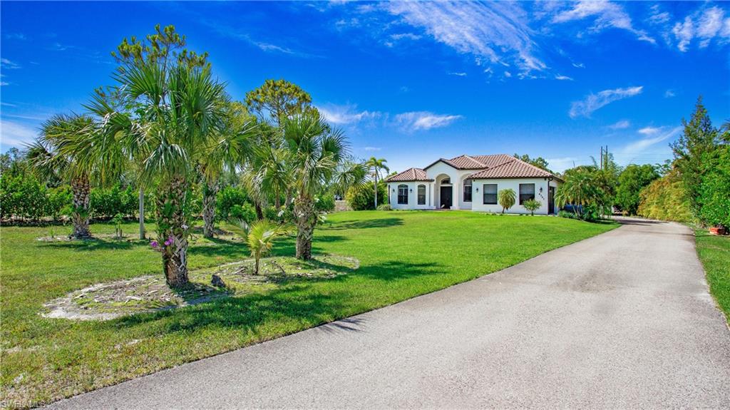 6341 Green Boulevard Naples, FL 34116 - Photo 4 of 48 Mediterranean / spanish-style house with a front lawn, a tiled roof, stucco siding, and driveway