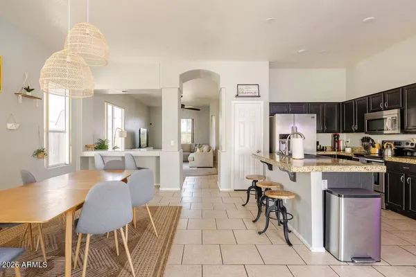 a very nice looking open dining room with kitchen island stainless steel appliances a table and chairs