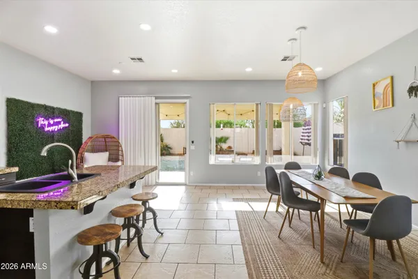a kitchen with stainless steel appliances kitchen island granite countertop a refrigerator a stove a sink a dining table and chairs with wooden floor