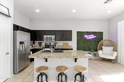 a kitchen with stainless steel appliances kitchen island granite countertop a refrigerator a stove a sink a dining table and chairs with wooden floor