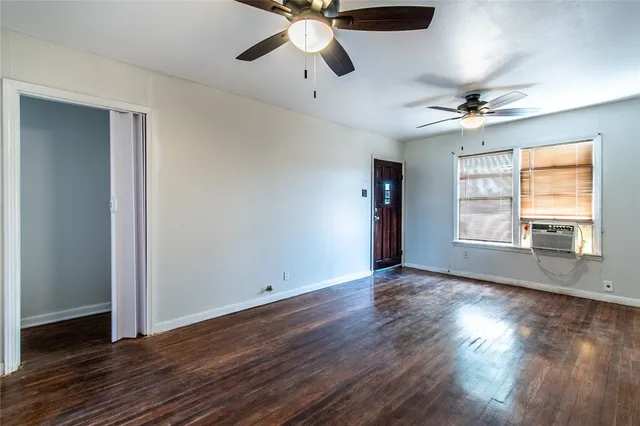a view of an empty room with wooden floor and a window
