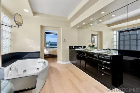 a spacious bathroom with a tub double sink and a mirror