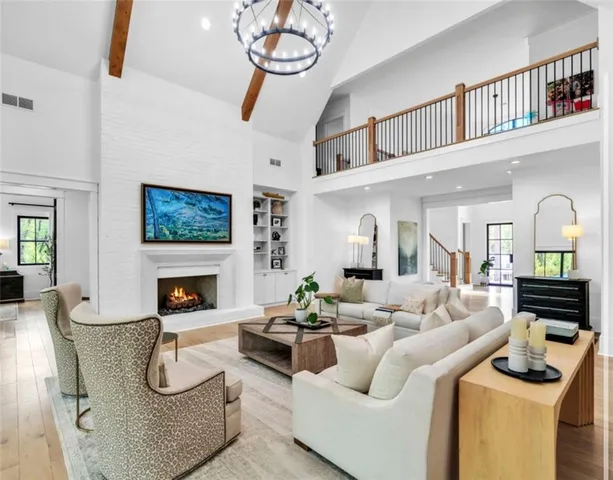 a view of a dining room and livingroom with furniture wooden floor a chandelier