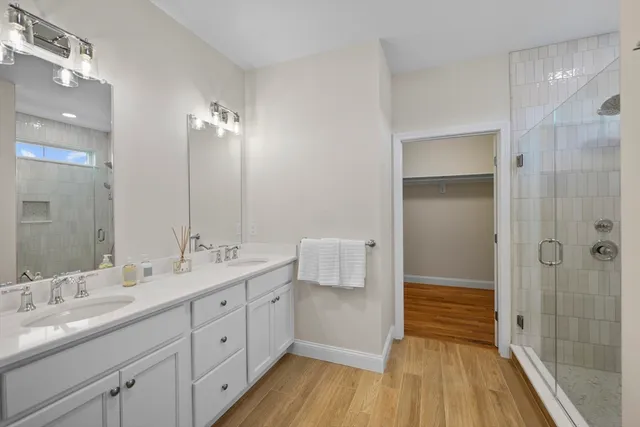 a spacious bathroom with a double vanity sink a mirror and a shower