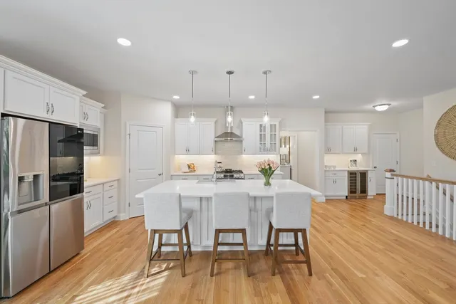 a kitchen with stainless steel appliances kitchen island granite countertop a dining table chairs refrigerator and sink