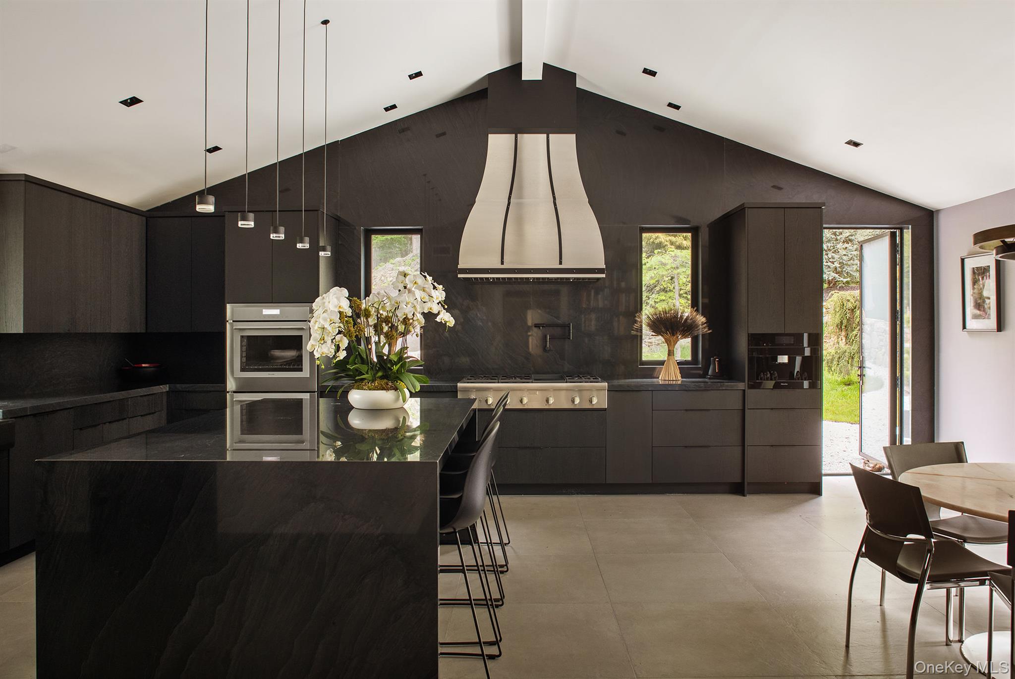 49 Indian Hill Road Pound Ridge, NY 10576 - Photo 14 of 34 a kitchen with kitchen island granite countertop a stove a refrigerator a sink a dining table and chairs with wooden floor