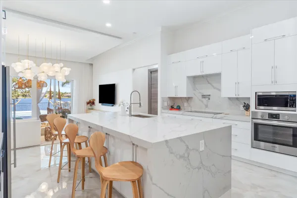 a kitchen with stainless steel appliances kitchen island a table chairs sink and cabinets