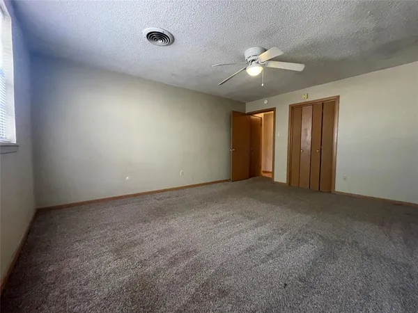 a view of an empty room with a ceiling fan and window
