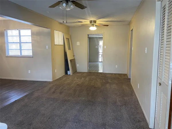 en empty room with chandelier fan and windows