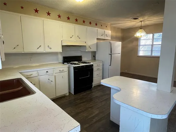 a kitchen with a sink a stove a refrigerator and white cabinets