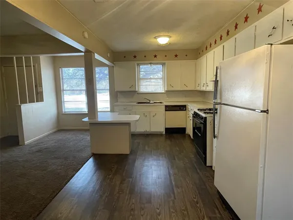 a kitchen with refrigerator a stove a sink and white cabinets with wooden floor