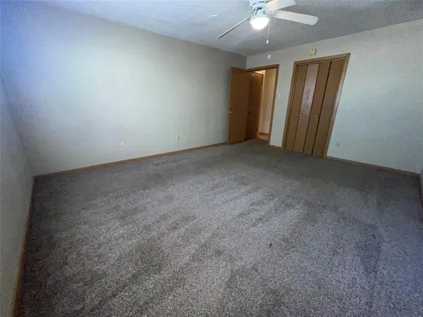 an empty room with a chandelier fan and windows