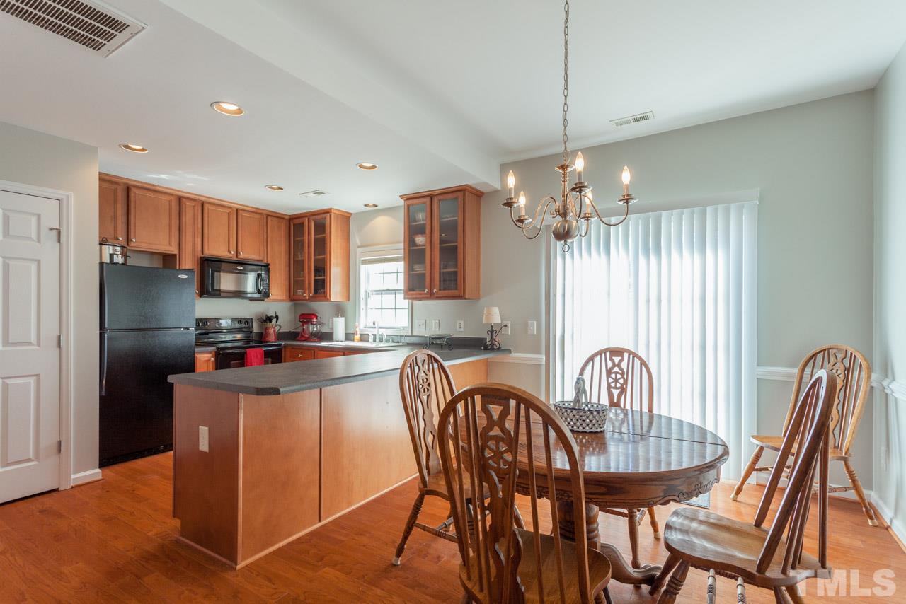 2120 Piney Brook Road, Unit 102 Raleigh, NC 27614 - Photo 9 of 24 a kitchen with stainless steel appliances granite countertop a table chairs and a refrigerator