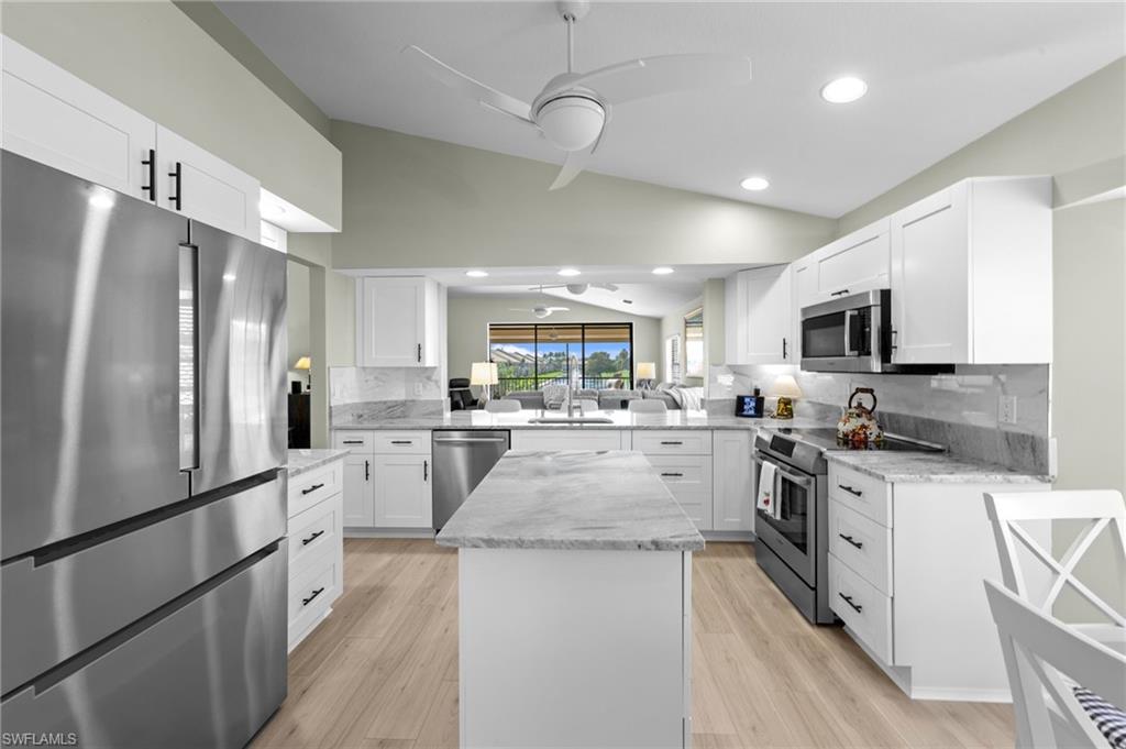 5720 Grande Reserve Way, Unit 2004 Naples, FL 34110 - Photo 7 of 27 a kitchen with white cabinets and stainless steel appliances