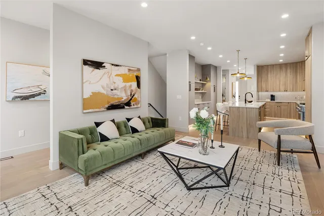 a kitchen with stainless steel appliances kitchen island granite countertop a refrigerator a sink dishwasher a stove and white cabinets with wooden floor