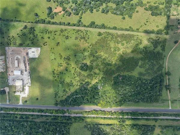 an aerial view of a residential houses with outdoor space and trees