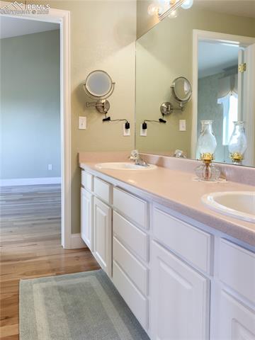 9385 Winged Foot Road Peyton, CO 80831 - Photo 22 of 50 "Jack-and-Jill" Main-level Full Bathroom featuring a double vanity and light wood finished floors, enclosed entrance to water closet/shower/tub combo