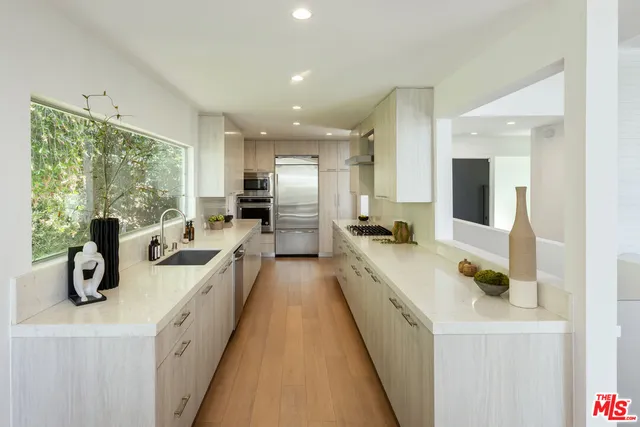 a large kitchen with stainless steel appliances a lot of counter space a sink and a refrigerator