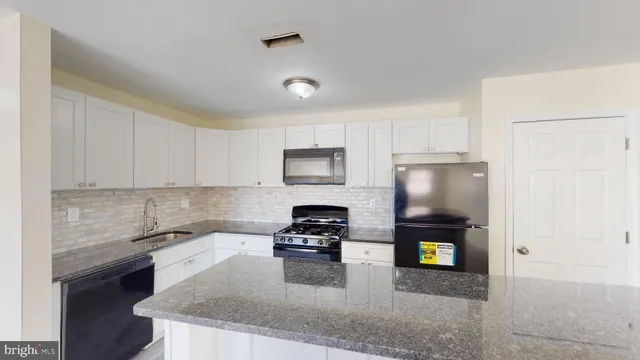 a kitchen with granite countertop a refrigerator sink and stove