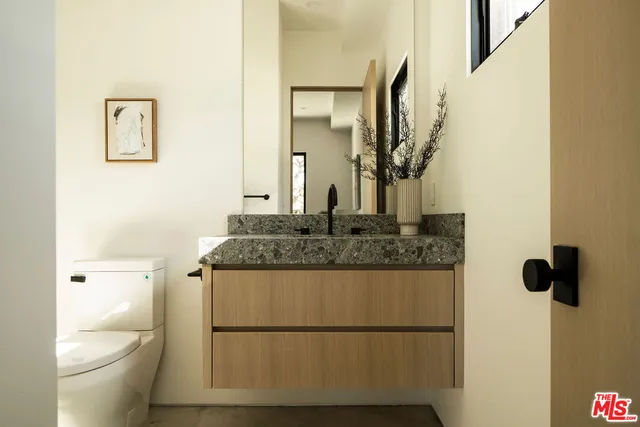 a bathroom with a granite countertop sink a toilet and a mirror