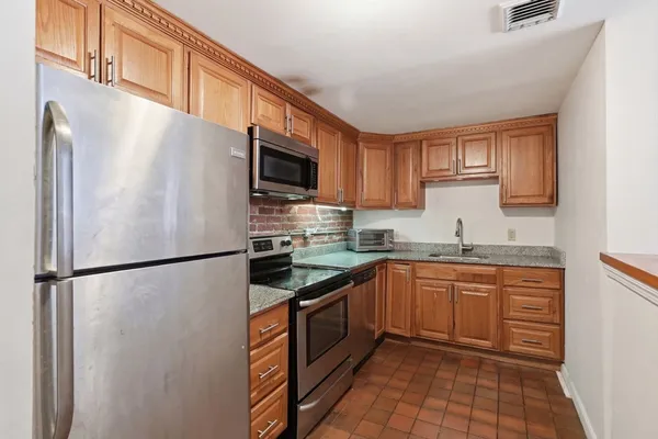 a kitchen with stainless steel appliances granite countertop a refrigerator a stove a sink dishwasher and a refrigerator