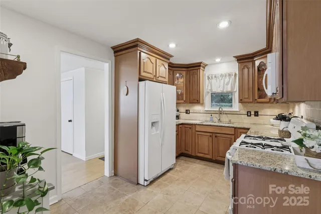 a kitchen with granite countertop a refrigerator a sink a stove and cabinets