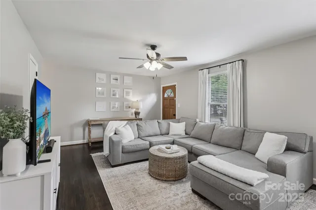 a living room with furniture a flat screen tv and a large window