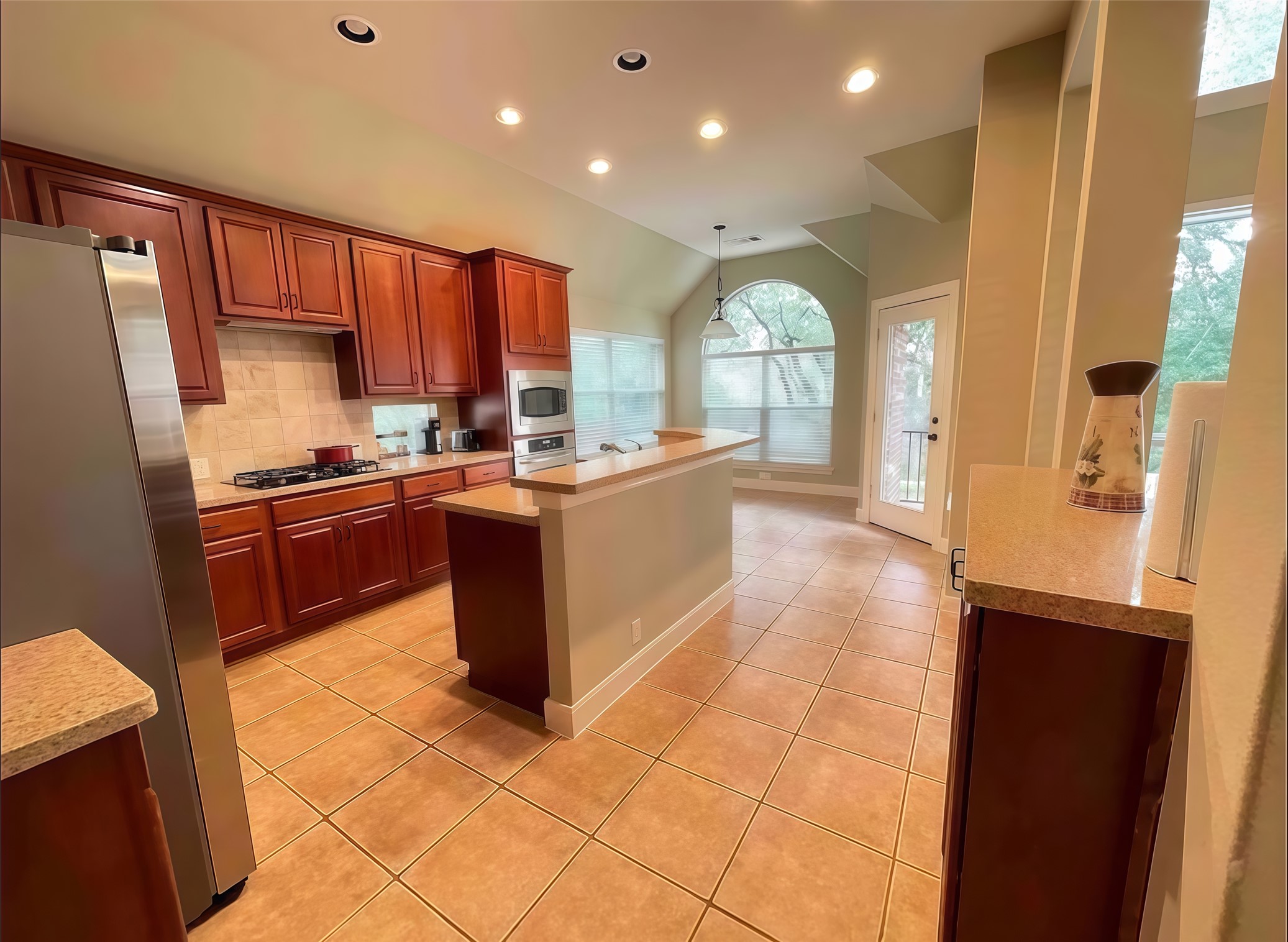 12616 Alberta Ridge Trail Austin, TX 78726 - Photo 3 of 26 Rich wood cabinetry and expansive tile floors anchor this vaulted kitchen with built-in appliances.