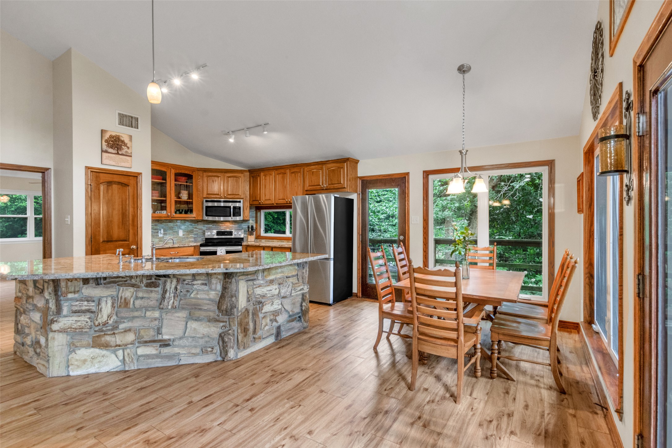 9997 Calhoun Road Bryan, TX 77808 - Photo 11 of 28 Warm wood flooring pairs with stone-accented cabinetry and wooded views through generous glazing.