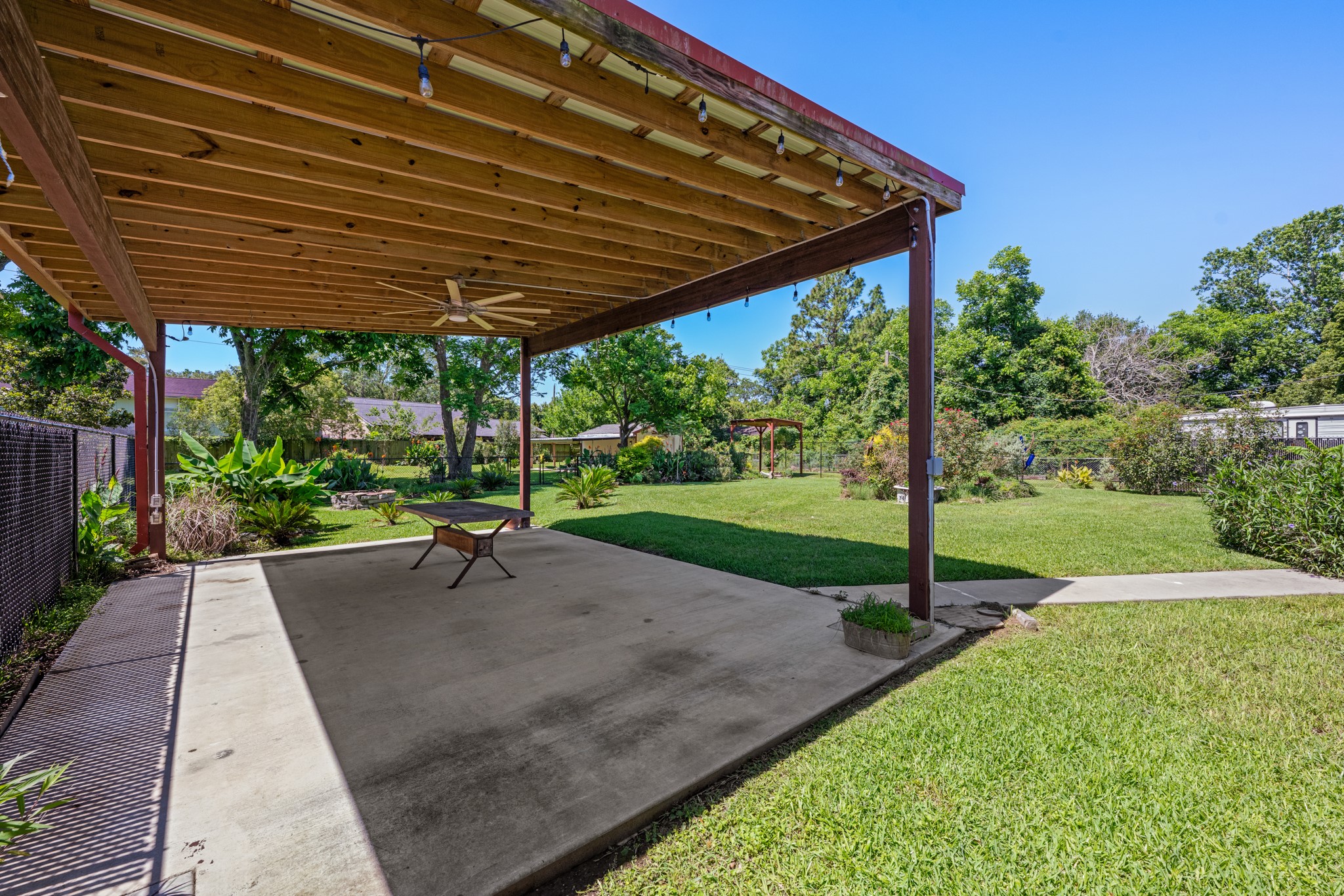 616 Cannan Drive Angleton, TX 77515 - Photo 30 of 49 Expansive covered patio provides a shaded space for outdoor dining, entertaining, or relaxing year-round. The generously sized backyard features mature landscaping, open green space, and established trees that create a peaceful outdoor setting.