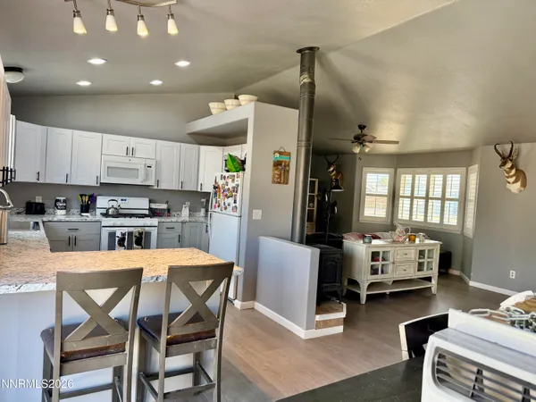 a kitchen with stainless steel appliances kitchen island granite countertop a dining table chairs refrigerator and sink