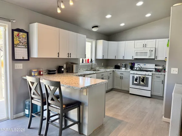 a kitchen with stainless steel appliances granite countertop a table chairs sink and cabinets