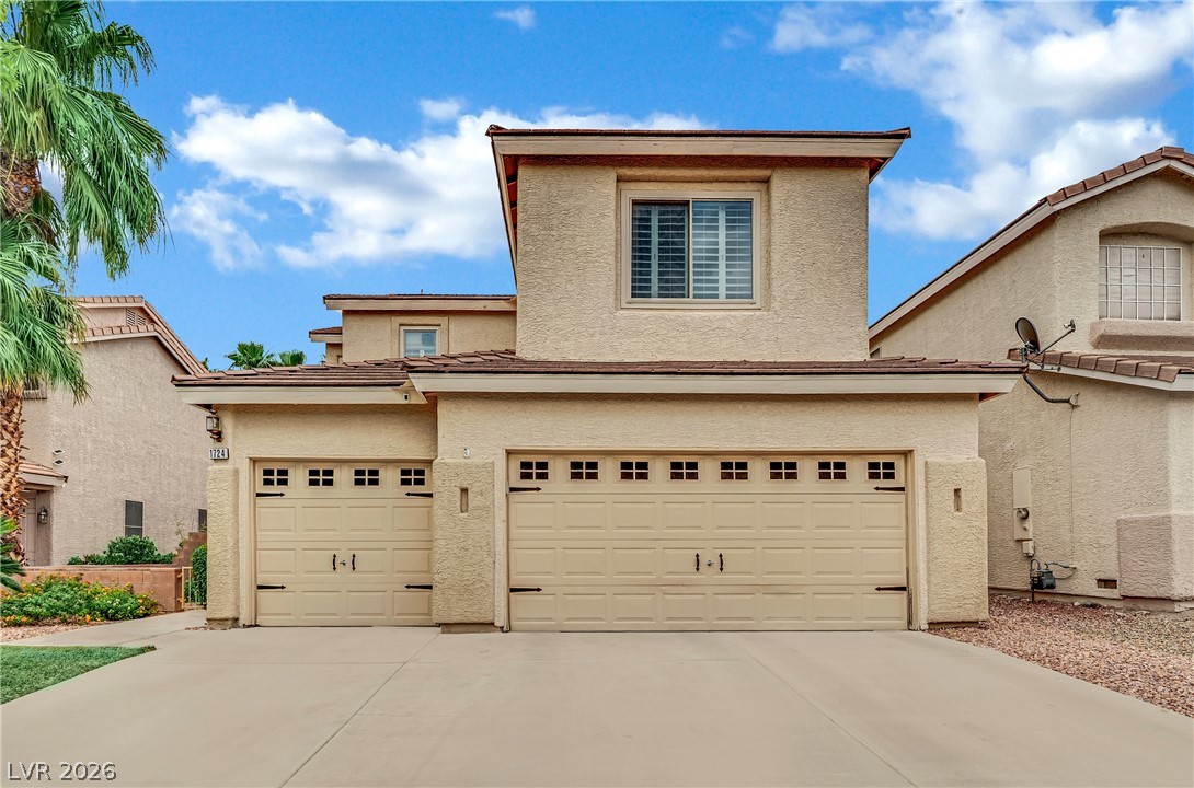 1724 Millstream Way Henderson, NV 89074 - Photo 2 of 60 A classic two-story stucco home features a dual garage and low-maintenance landscaping.