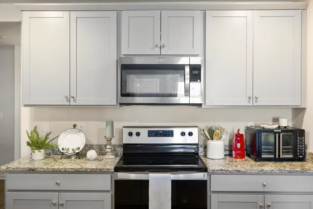 a kitchen with granite countertop white cabinets and stainless steel appliances
