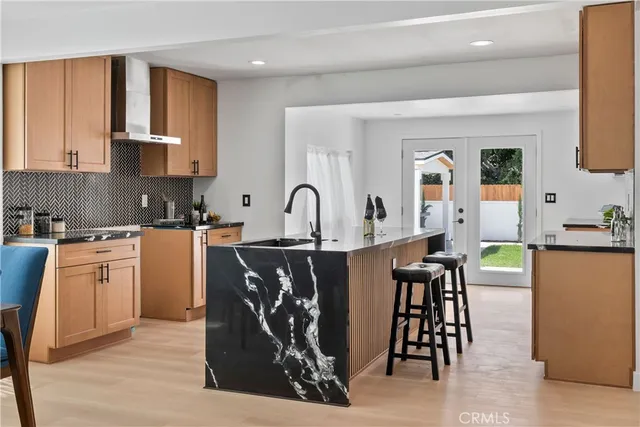 a kitchen with stainless steel appliances granite countertop a stove top oven a sink a dining table and chairs with wooden floor