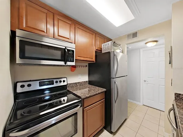 a kitchen with granite countertop a refrigerator and a stove top oven