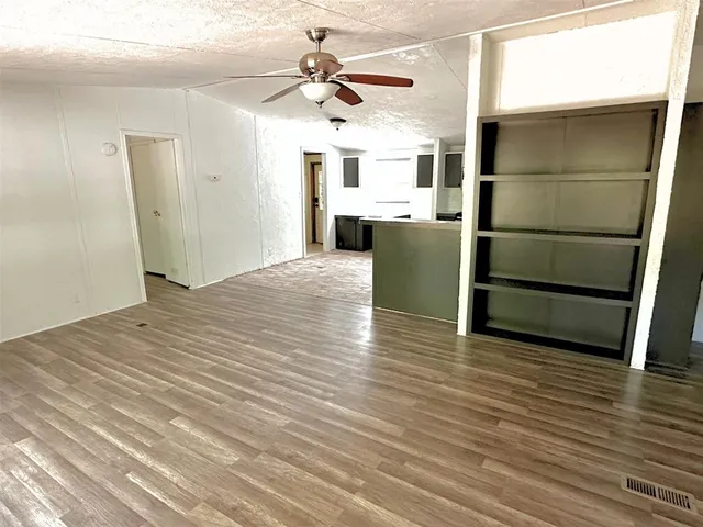 a view of kitchen and empty room with wooden floor