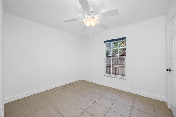 an empty room with windows and ceiling fan