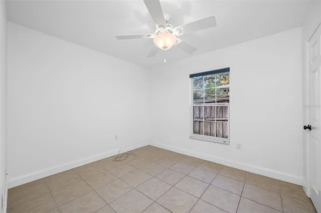 an empty room with windows and ceiling fan