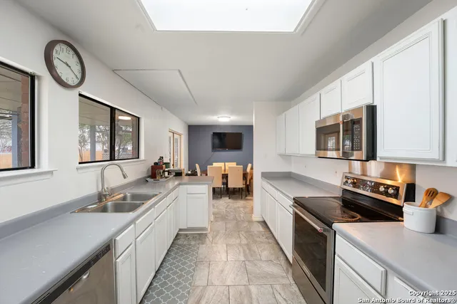 a large kitchen with stainless steel appliances granite countertop a lot of counter space and a sink