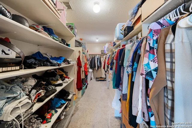 a view of walk in closet with clothes and shoes