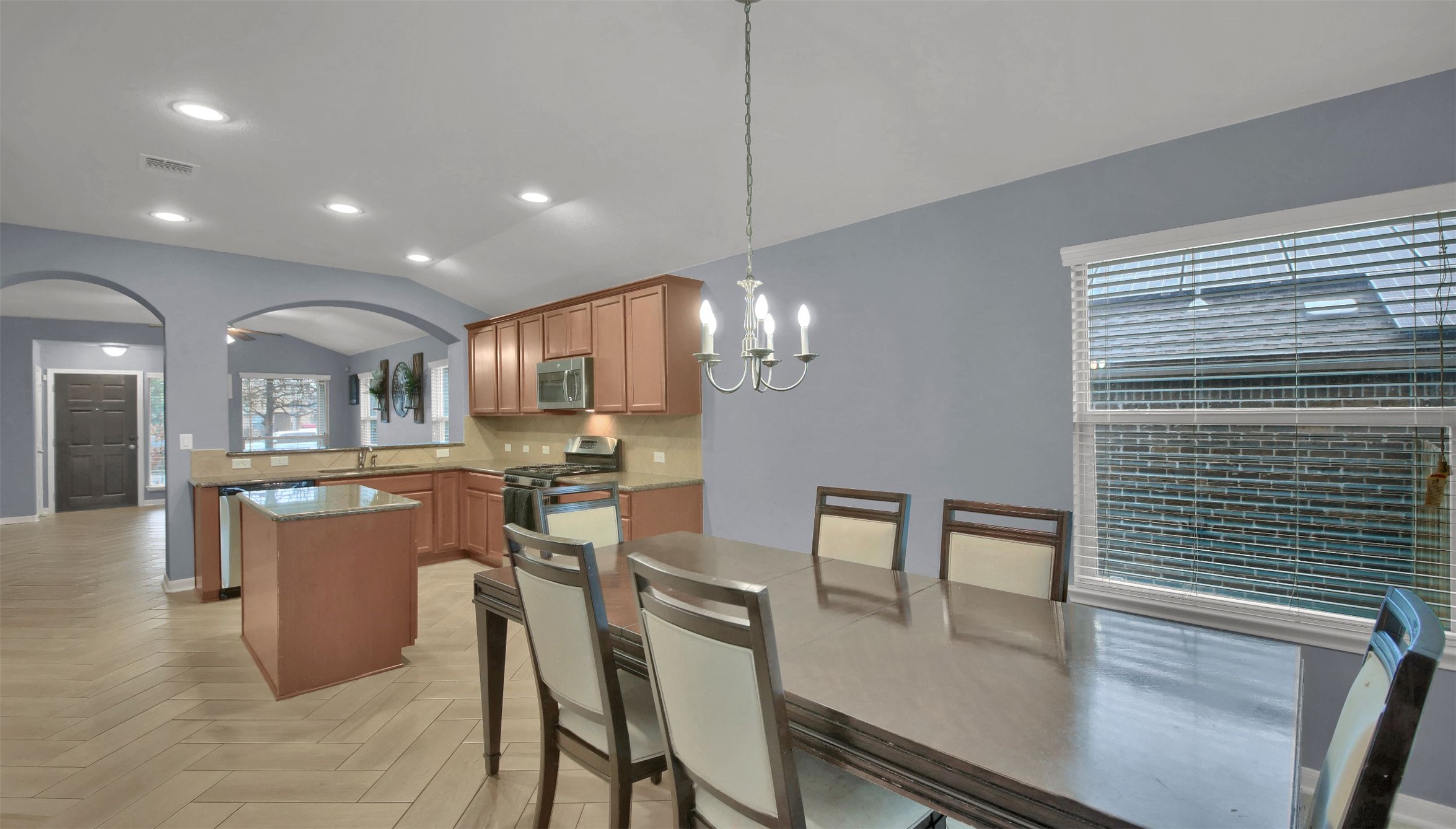 18005 Moreto Loop Pflugerville, TX 78660 - Photo 14 of 25 Kitchen featuring brown cabinetry, recessed lighting, pendant lighting, a chandelier, and lofted ceiling