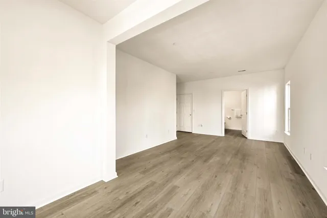 a view of an empty room with wooden floor and closet