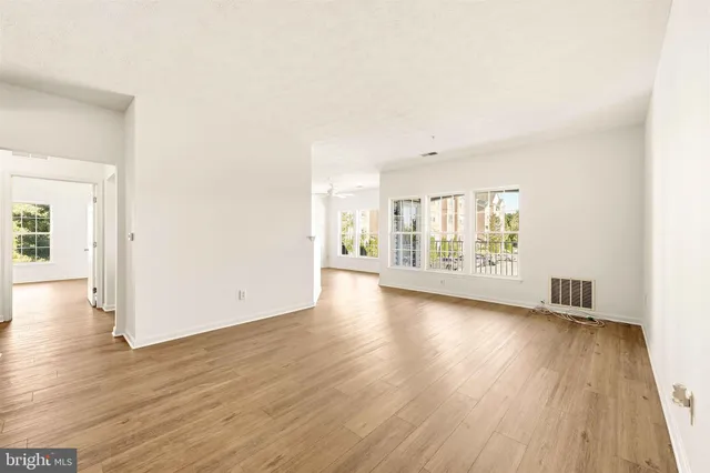 an empty room with wooden floor and windows