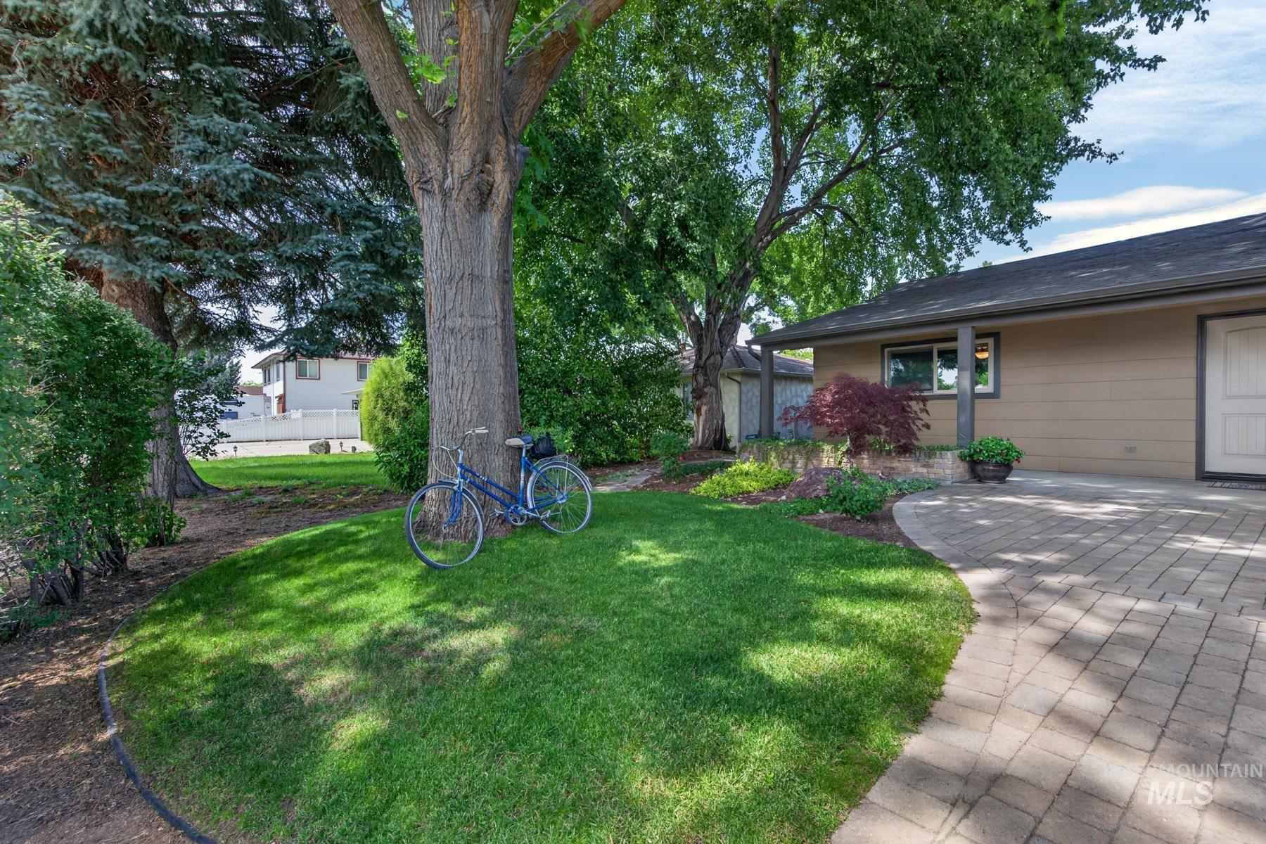 9622 Delaware Street Boise, ID 83709 - Photo 4 of 48 Mature tree canopy providing shade, manicured lawn, paver stone walkway, and a landscaped garden bed with varied plantings