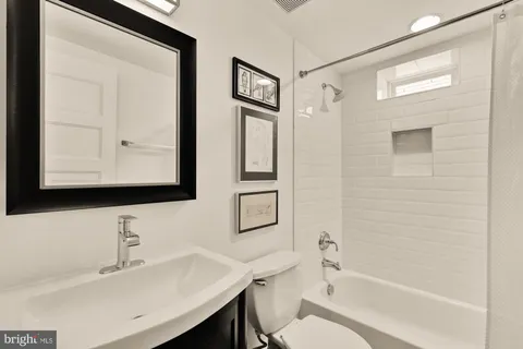a bathroom with a bathtub shower sink and mirror
