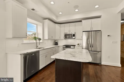 a kitchen with a sink a refrigerator a center island and cabinets