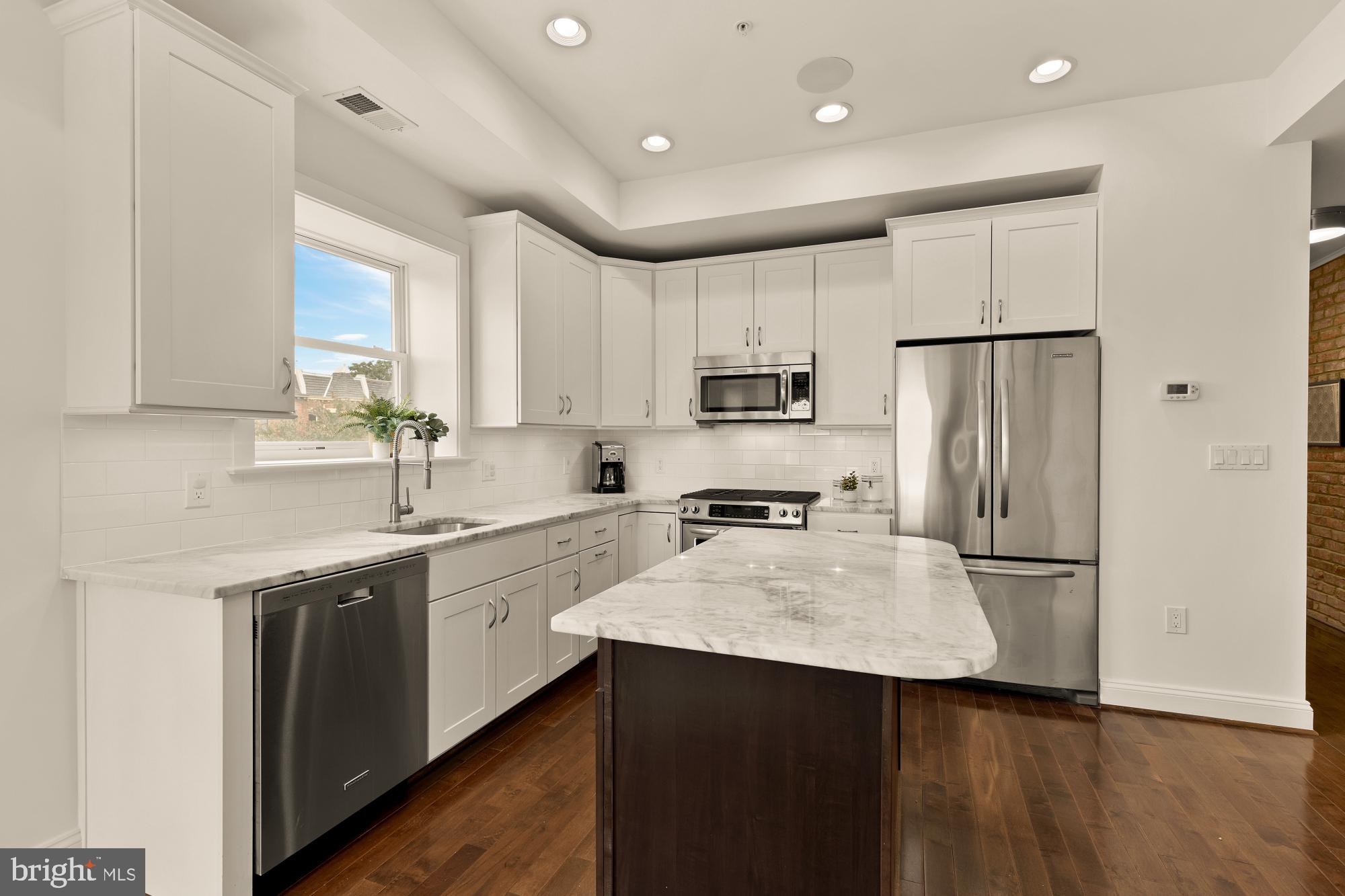 1249 Kenyon Street Northwest, Unit 4 Washington, DC 20010 - Photo 7 of 30 a kitchen with a sink a refrigerator a center island and cabinets