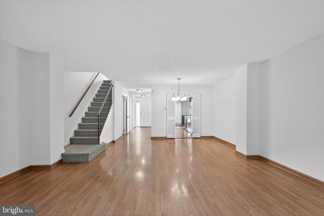 a view of an empty room with wooden floor and stairs