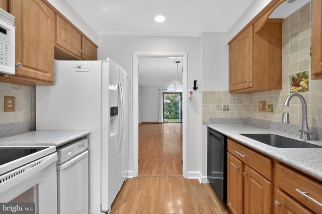 a kitchen with stainless steel appliances granite countertop a refrigerator a sink dishwasher and white cabinets with wooden floor